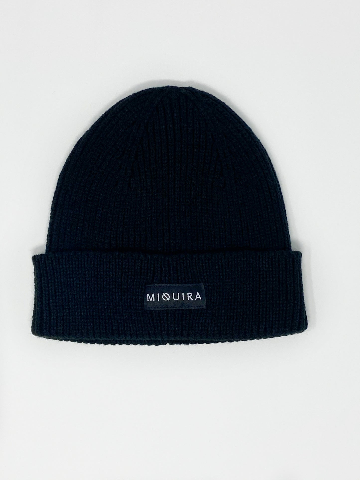 Black acrylic knitted beanie with black Miquira label stitched on the outside.