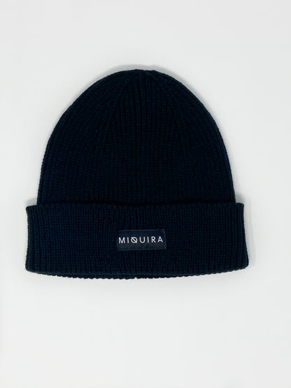 Black acrylic knitted beanie with black Miquira label stitched on the outside.