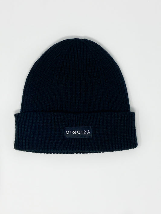 Black acrylic knitted beanie with black Miquira label stitched on the outside.